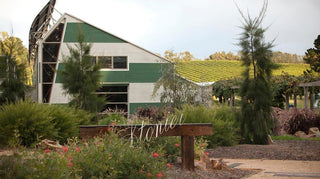 the image shows stonier seller door with vineyards as the backdrop. always infron is a metal structure holding a stainless steel stonier sign