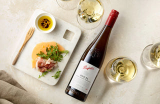 Bottle of Wolf Blass wine with a platter of food and glasses on a light surface