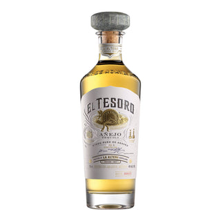 El Tesoro Añejo Tequila 750ml features a clear glass bottle with gold liquid, a decorative cork top, and an intricate white and gold label with agave imagery. Offers notes of cooked agave and toasted oak.