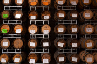 Rows of wooden barrels with labels in a storage facility