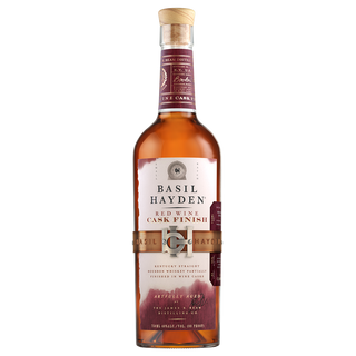 A bottle of Basil Hayden Red Wine Cask Finish Bourbon with a wooden cork and maroon label featuring gold and white text sits on a plain white background—inside, enjoy notes of dried fruits and bourbon sweetness.