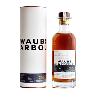 A bottle of Waubs Harbour Original Tasmanian Single Malt Whisky with a cork stopper stands beside its sleek white tube packaging, both adorned with modern black and gold branding. The amber whisky reveals aromas of spiced apple crumble.