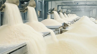 Textile production line with large spools of white yarn in a factory setting.