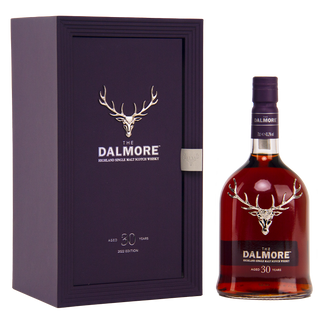 A bottle of The Dalmore 30 Year Old Single Malt Scotch Whisky stands beside its dark purple box featuring a silver stag logo and text highlighting it as a Highland single malt aged 30 years, with notes of Morello cherries and dark chocolate.