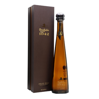 A tall, elegant bottle of Don Julio 1942 Añejo Tequila 750ml with a dark cap stands beside its matching brown and gold box on a white background, offering rich notes of vanilla and honeyed agave in every sip.