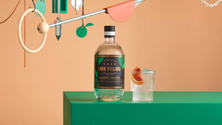 Bottle of Four Pillars Gin on a green surface with a colorful abstract background