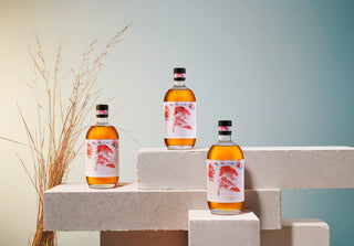 Three bottles of a beverage on a geometric platform with a minimal background