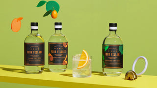 Three bottles of Four Pillars gin on a yellow surface with a green background
