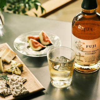 A bottle of Fuji Single Grain Japanese Whisky and a glass of ice cubes, perfect for mixing with notes of white grape.