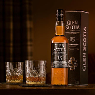 A bottle of Glen Scotia 15 Year Old Single Malt Scotch Whisky and its box sit beside two glasses on a wooden surface in warm light, evoking citrus zest and rich dark chocolate notes.