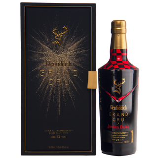 A black and gold Glenfiddich Grand Cru 23 Year Old x Jordan Dalah Box Set stands open, revealing a matching bottle with gold accents, red checkers, and the Glenfiddich logo—evoking notes of sandalwood and peach.