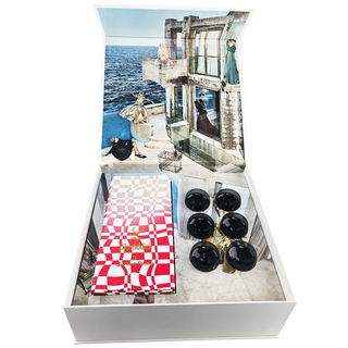 An open white Glenfiddich Grand Cru 23 Year Old x Jordan Dalah Box Set displays five black spheres, a red-and-white checkered packet, and an interior lid with a stylish collage evoking hints of brioche and banana.