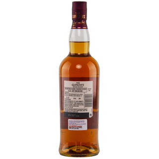 A bottle of The Glenlivet 15 Year Old French Oak Reserve Single Malt Scotch Whisky shown from the back, featuring its label and maroon cap. The amber liquid inside offers notes of baked apple and a creamy texture.