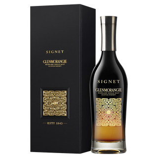 A Glenmorangie Signet Single Malt Scotch Whisky bottle with a gold pattern and black label sits beside its matching black and gold box on a white background, evoking notes of rich mocha and dark chocolate.