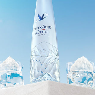 Clear bottle labeled 'Grey Goose Altius' with ice sculptures against a blue sky.