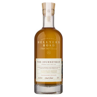 A clear glass bottle of Hellyers Road The Journeyman Single Malt Tasmanian Whisky features a wooden cork, gold label with white and brown text, noting bourbon and port cask aging, and aromas of oak spice, caramel, and citrus.