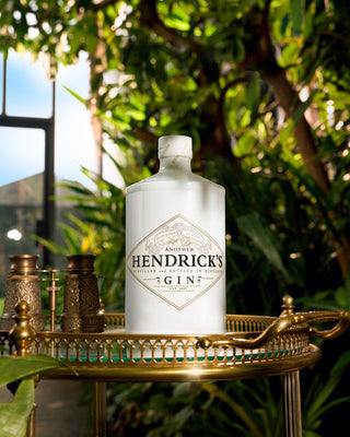 Hendrick's Gin bottle on a decorative tray with a blurred green outdoor background