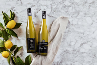 Two bottles of Hennessy cognac on a marble surface with lemons and leaves.