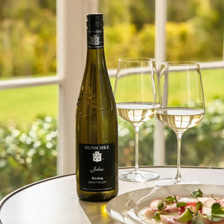 Bottle of Henschke wine with two glasses on a table with a blurred outdoor background