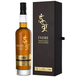 A bottle of Indri Drú Cask Strength Single Malt Indian Whisky with a gold and black label stands beside its matching box, both displaying the Indri logo, and offers notes of chocolate and ripe fruit.