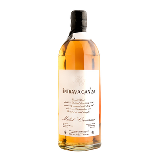 A bottle of Michel Couvreur Intravagan’za French whisky, featuring a white label, black cap, and golden amber liquid, celebrated for its smooth malt character with subtle orchard fruit notes, stands on a plain white background.