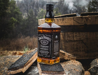 Jack Daniel's Tennessee Whiskey bottle on a wooden barrel with a forest background