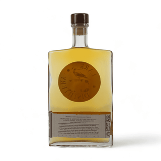 A clear glass bottle of Torrijas Azafranes by La Distillerie, filled with golden amber liquid and topped with a dark brown cap, set against a plain white background.