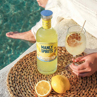 Bottle of Manly Spirits by the pool with a glass of lemonade.