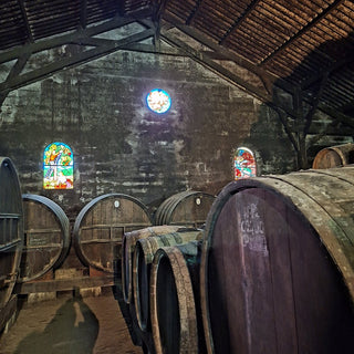 Wine barrels in a aging cellar with stained glass windows.