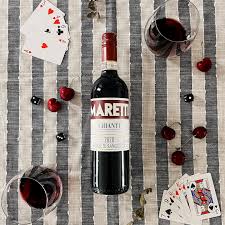Bottle of Maretto wine with playing cards and glasses on a striped tablecloth