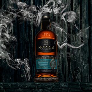 A bottle of Morris Whisky Smoked Sherry Australian Single Malt Whisky stands against a dark wooden backdrop, with swirling smoke hinting at sherry sweetness and spiced oak notes.