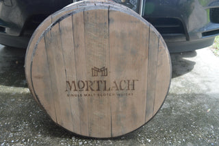 Wooden barrel with Mortlach Single Malt Scotch Whisky logo on a road.