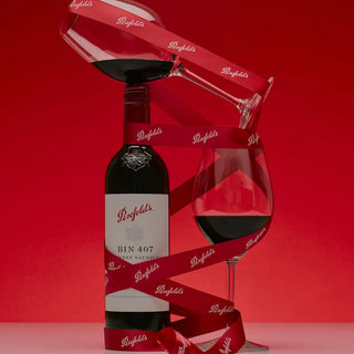 Penfolds wine bottle and glass with red ribbon on a red background