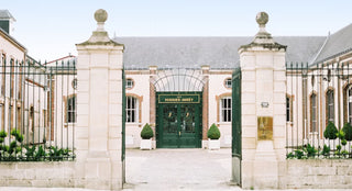 Elegant building entrance with stone pillars and a green door, featuring the Veuve Clicquot logo.