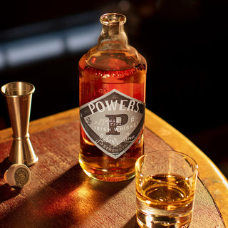 Bottle of Powers Irish Whiskey with a glass on a wooden surface