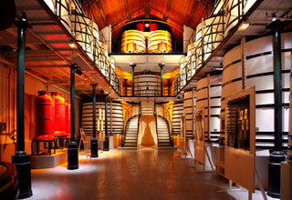 Large warehouse with rows of cylindrical tanks and a central staircase.