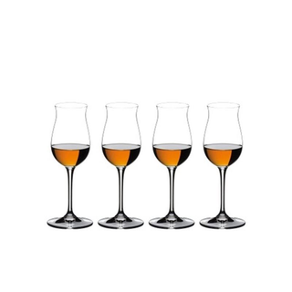 Four wine glasses filled with different levels of amber liquid on a white background
