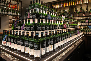 Tall pyramid of Johnnie Walker bottles on a bar counter with shelves in the background