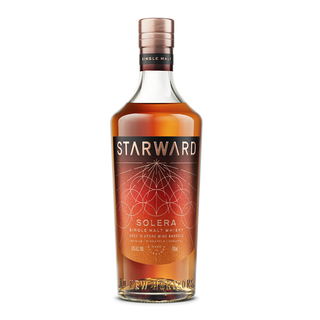 A bottle of Starward Solera Australian Whisky with a copper cap and a reddish-brown label adorned with geometric gold details, set on a white background; highlights flavors of ripe orchard fruit and caramel chews.