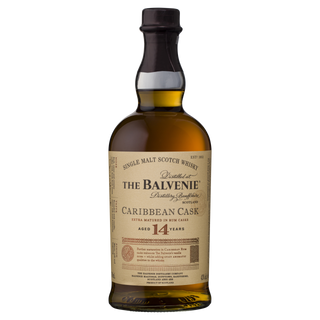 A bottle of The Balvenie Caribbean Cask 14 Year Old Single Malt Scotch Whisky with a cream label, dark brown cap, and gold and black text detailing its aging process and smooth tropical vanilla notes.