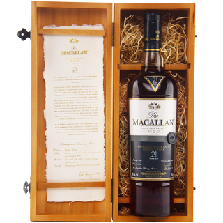 A bottle of The Macallan 21 Year Old Fine Oak Single Malt Whisky in a wooden gift box with straw, featuring sherry and vanilla notes, plus a scroll-style whisky description on the inside lid.