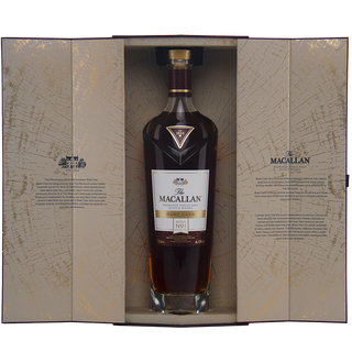 A bottle of The Macallan Rare Cask Release Batch No. 1 Single Malt Scotch Whisky, with sweet sherry and blossom honey notes, is displayed upright in an open cream and gold box featuring text and a castle illustration on the inner flaps.