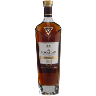 A bottle of The Macallan Rare Cask Release Batch No. 1 Single Malt Scotch Whisky in a tall, clear glass bottle with a gold cap and white-and-gold label, offering rich amber whisky with sweet sherry and blossom honey notes.