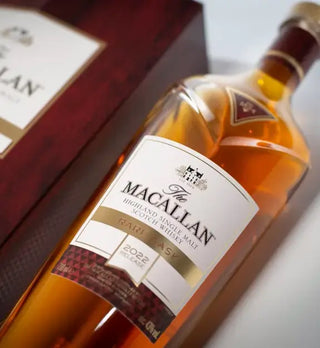 A close-up of The Macallan Rare Cask Single Malt Scotch Whisky (2022 Release), with its maroon and gold box. The amber whisky offers vanilla and sherry sweetness notes.