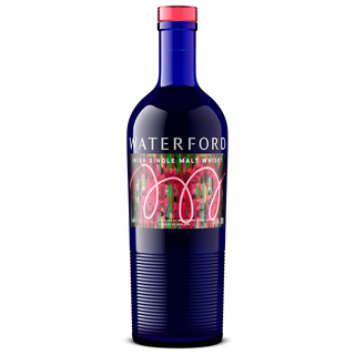 A blue glass bottle of Waterford The Cuvée Single Malt Whisky with a vibrant, abstract label in pink, green, and red. The ribbed lower section and pink cap complete the look. Inside: rich malt and orchard fruit notes await.
