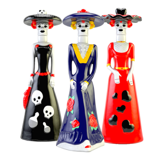 Doña Celia Añejo Tequila 100ml comes in three vibrant ceramic Catrina figurines, each adorned with decorative hats and dresses featuring skull and rose motifs—celebrating the lively Day of the Dead spirit.