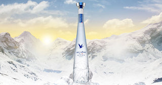 Clear bottle with blue label against a snowy mountain landscape