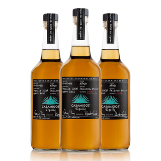 Three Casamigos Anejo Tequila 700ml bottles stand side by side against a white background, their amber color and sleek black labels hinting at notes of roasted agave and sweet oak.