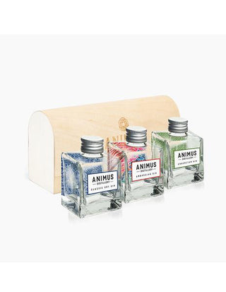 Three square glass bottles of Animus Distillery Sample Pack (300ML), each with a distinct label, are arranged before a light wooden box with a curved lid, highlighting the unique cool-climate native botanical flavors.