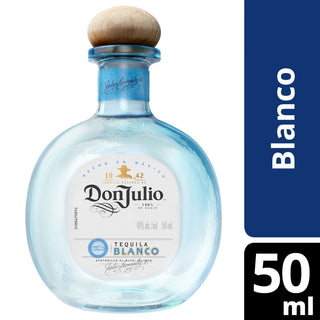 A clear glass Don Julio Blanco Tequila 50ml bottle with a wooden cap features a blue-bordered label showing "Blanco" and "50 ml" in bold white text. Crafted from blue agave.